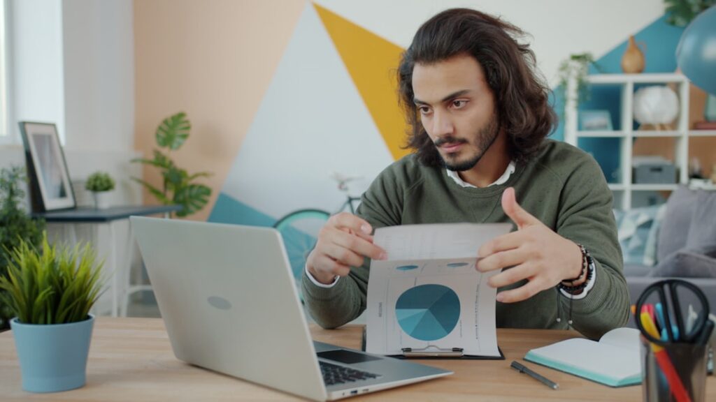 Business owner reviewing documents and laptop for compliance planning