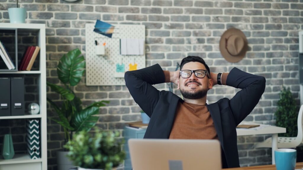 Businessman relaxing at desk with hands behind head in modern office