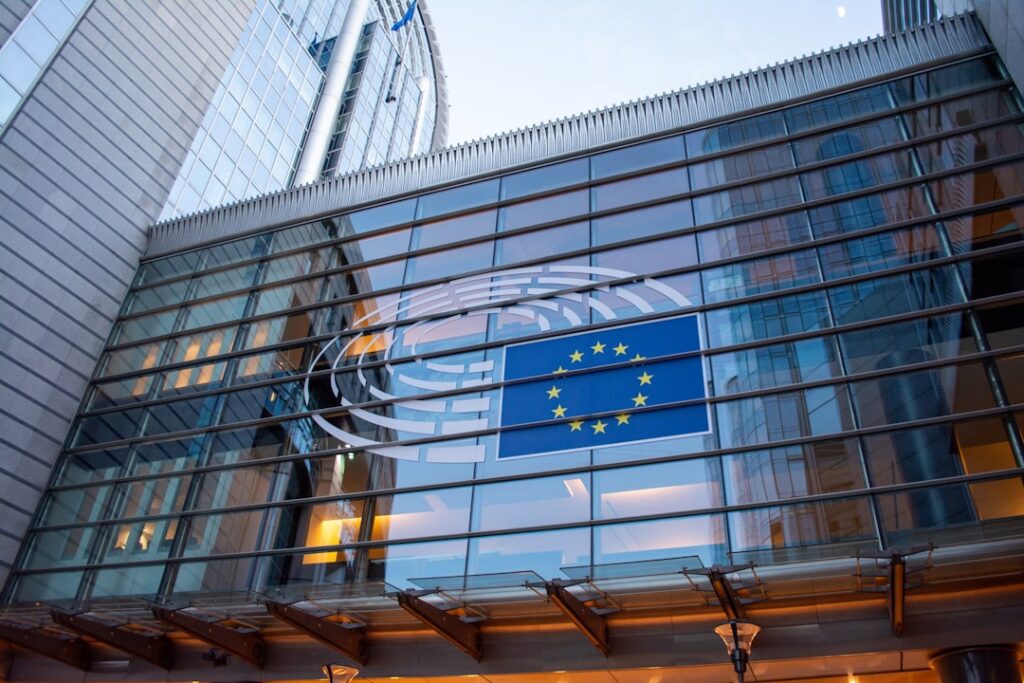 European Union flags reflected on modern Parliament building glass facade